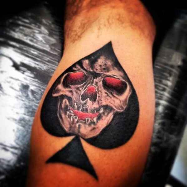 Stunning spades symbol stylized with skull colored tattoo on leg