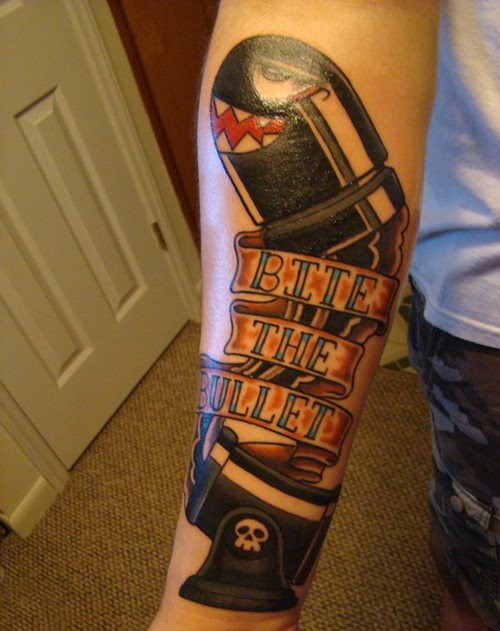 Tatuaje en el antebrazo, bala divertida de videojuego y cinta con inscripción