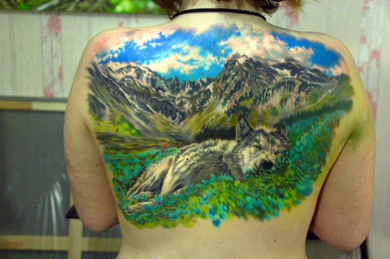 Stylish natural looking realism style upper back tattoo of wolf sleeping near mountains