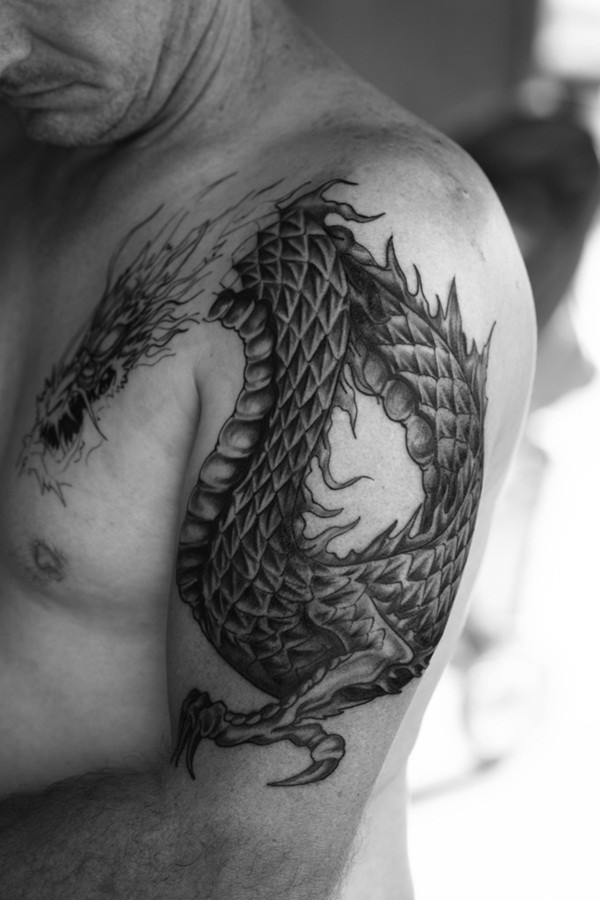 Stylish painted detailed black and white dragon tattoo on shoulder stylized with flames