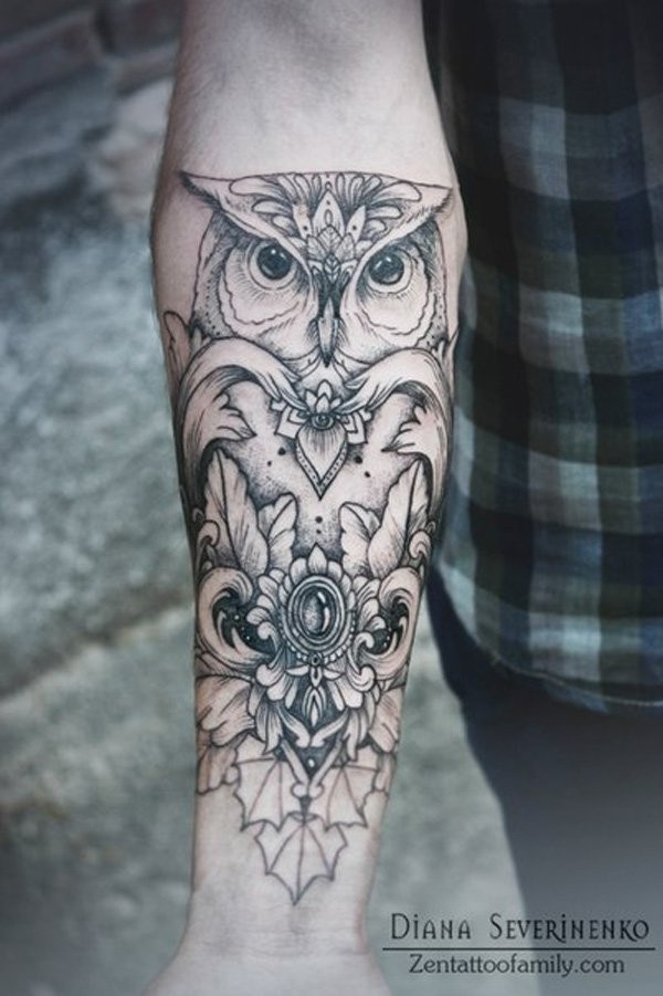 Stylized black owl tattoo on forearm