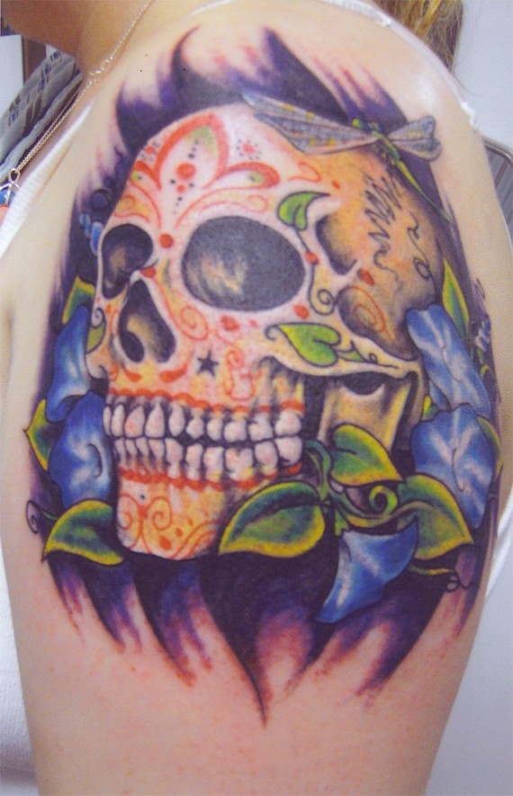 Tatuaggio colorato sul deltoide il teschio tra i fiori