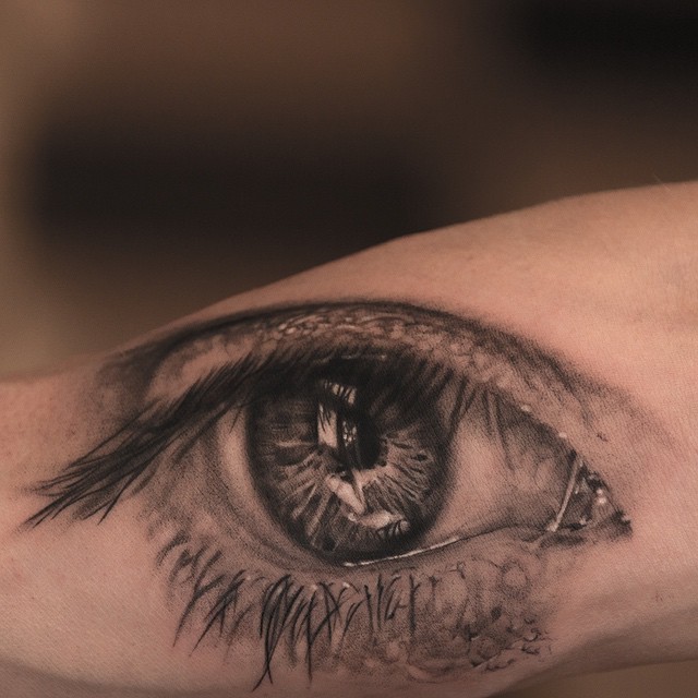 Super realistic human black gray eye tattoo on arm by Niki Norberg