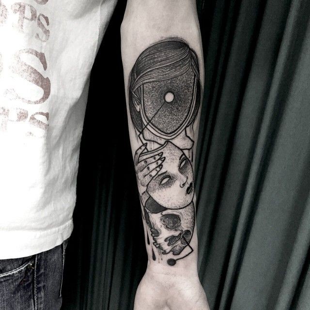 Surrealism style black ink forearm tattoo of human face with mask and skull