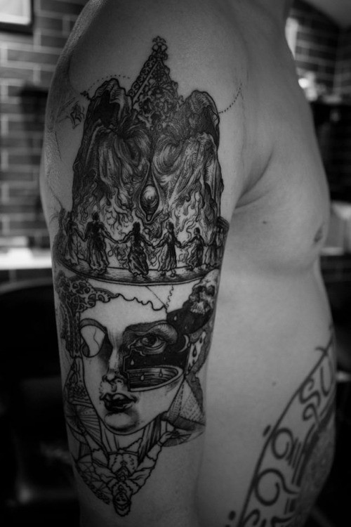 Surrealism style black ink shoulder tattoo of human face with creepy figures
