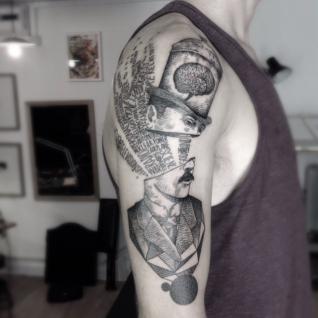 Surrealism style black ink shoulder tattoo of man with divided head and lettering