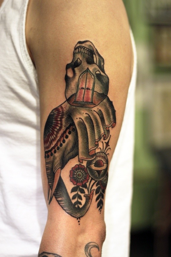 Surrealism style colored shoulder tattoo of elephant shaped head with skull and flowers