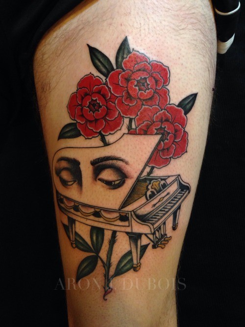Surrealism style colored thigh tattoo of piano with human eyes and flowers