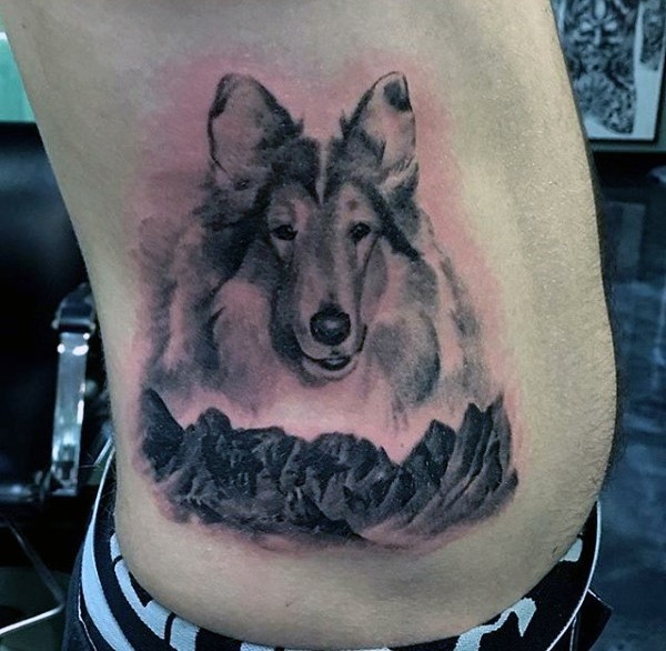 Süßer  schwarzweißer Hund und Berge Tattoo an der Seite