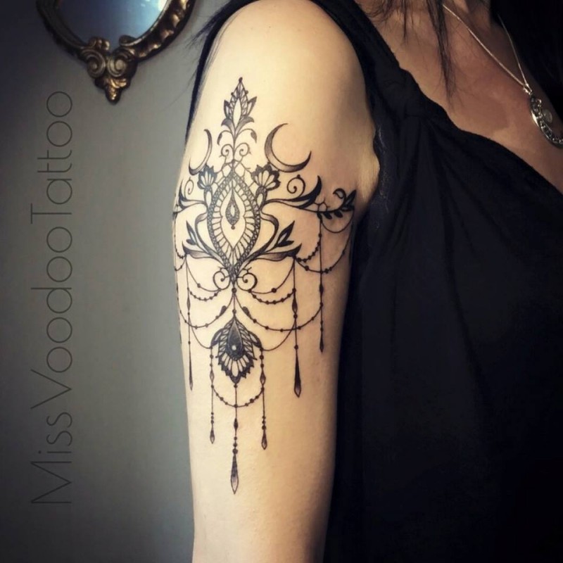 Sweet looking black ink painted by Caro Voodoo upper arm tattoo of floral ornaments with flowers