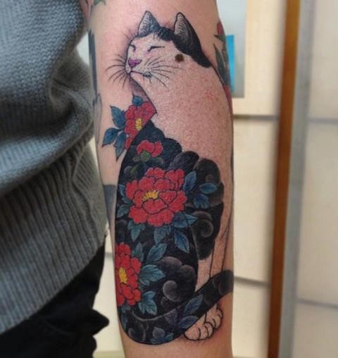 Sweet looking colored arm tattoo of Manmon cat stylized with red flowers