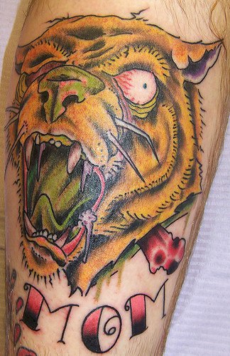 El tatuaje de color de un tigre loco con un solo ojo y la palabra &quotmama"