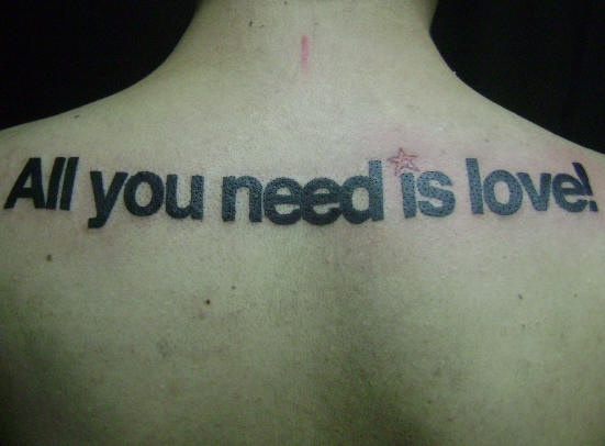 el tatuaje de la frase &quotall you need is love" &quotel amor es todo lo que necesitas" en la espalda