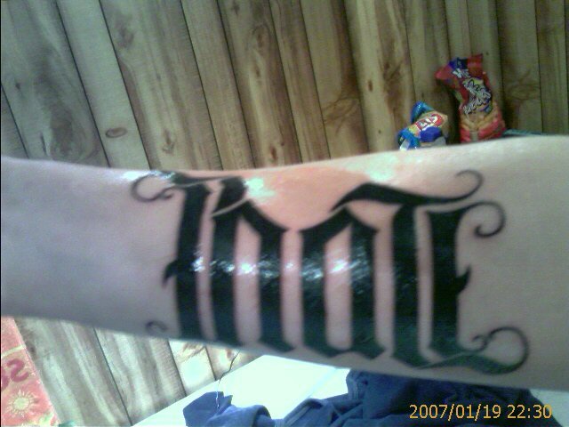 Ambigramma con la parola tatuato sul braccio