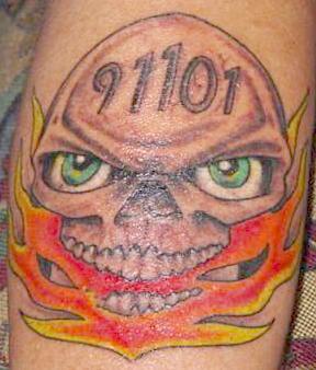 el tatuaje 911 de una calavera con ojos verdes y el fuego en su boca