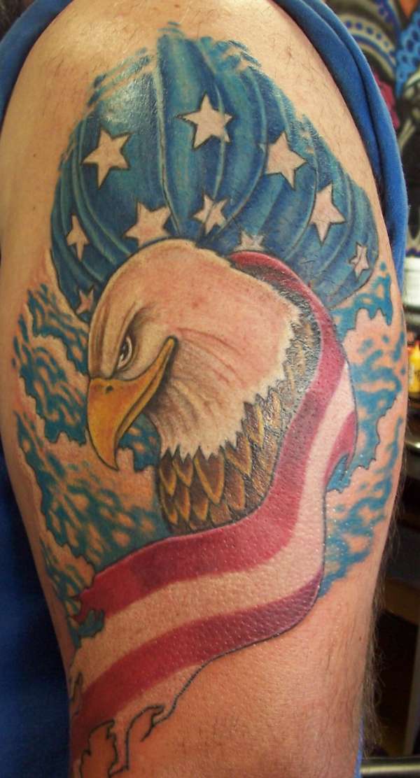el tatuaje muy bonito de una aguila con el fondo de colores iguales a los de la bandera americana