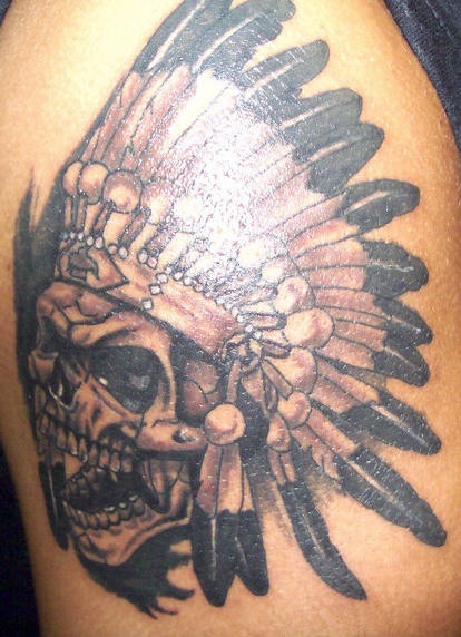 el tatuaje detallado de una calavera con corona de plumas hecho en color negro