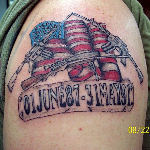 el tatuaje patriota con las fechas, la bandera americana y armas cruzadas