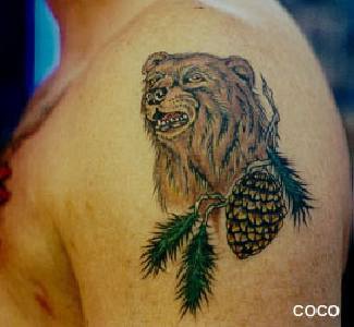 Tatuaje en el hombro de un oso pardo y un abeto en forma de cono.