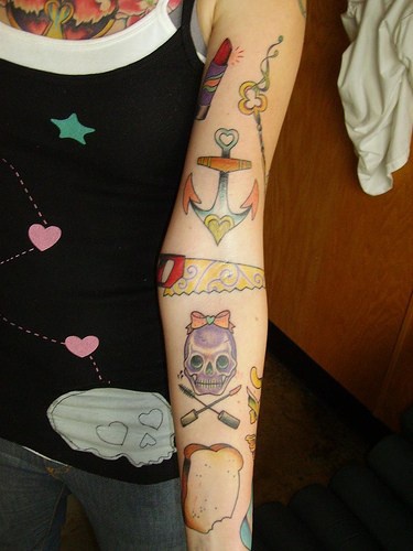 Pane tostato,  sega, ancora e teschio tatuati sul braccio