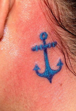 Kleiner blauer Anker Tattoo hinter dem Ohr