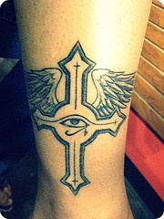 Cross with eye and wings ankle tattoo