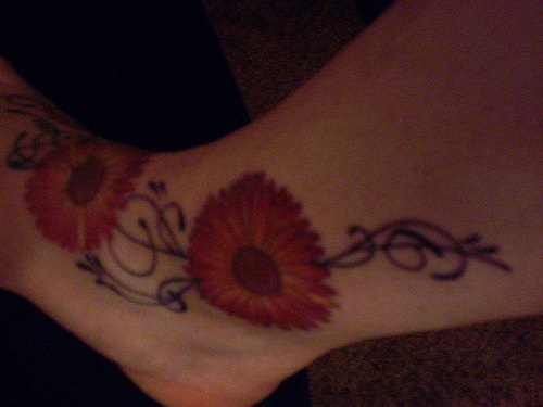 Tattoo von breiter roter Blume  in der Knöchelgegend