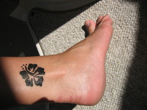 Une fleur noire ronde le tatouage sur la cheville