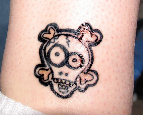 Tattoo vom  Totenkopf und Knochen in der Knöchelgegend