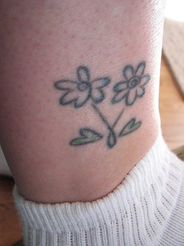 Tattoo von zwei verbogenen Blumen in der Knöchelgegend