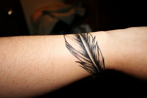 Tattoo vom nichtfarbigem Feder am Arm
