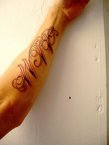 Tattoo von schön gestaltetem Aufschrift am Arm