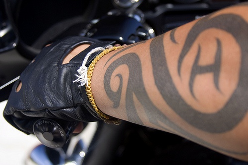 Tattoo von Schnörkeln und Lettern am Arm