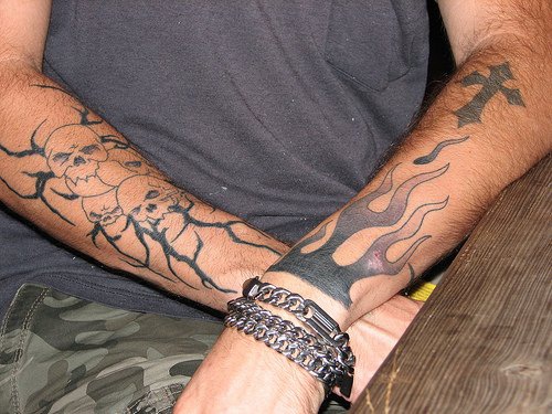 Tattoo von Totenkopf und Kreuz  am Arm