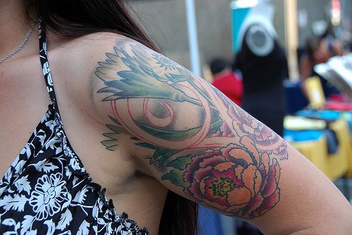 Flower-face arm tattoo