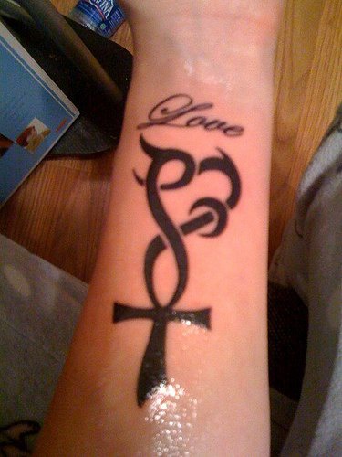 Tattoo von Kreuz und Herz am Arm
