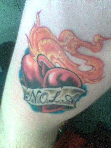 Cœur enflammé avec le tatouage sur le bras d&quotune inscription Nola