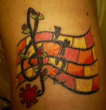 Tattoo mit Violinschlüssel und Notenlinien am Arm