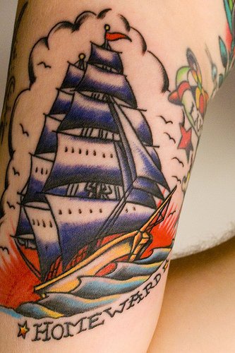 Tattoo vom Schiff mit Aufschrift &quotNach Hause" am Arm