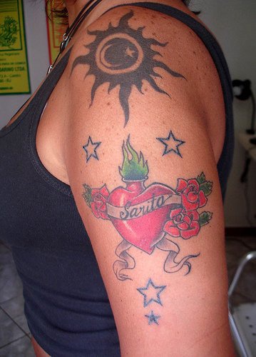 Tattoo von schön gestaltetem Herzen, der Sonne und Sternen am Arm