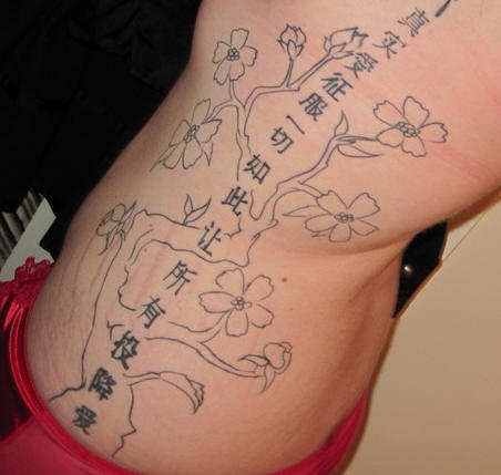 Le tatouage asiatique sur le flanc avec beaucoup d&quothiéroglyphes en fleurs