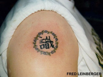 Tatuaje en el hombro de jeroglíficos asiáticos en circulo.
