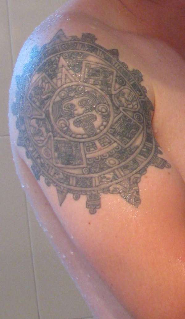 Black sun stone tattoo on shoulder