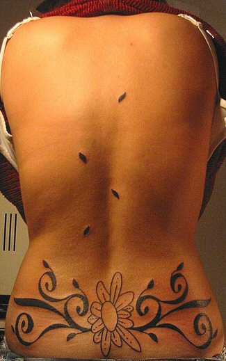 Tatuaje en la espalda de mujer con flores grandes.