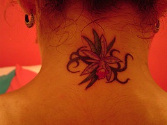 Elegantes Tattoo mit kleine Blume am Hals