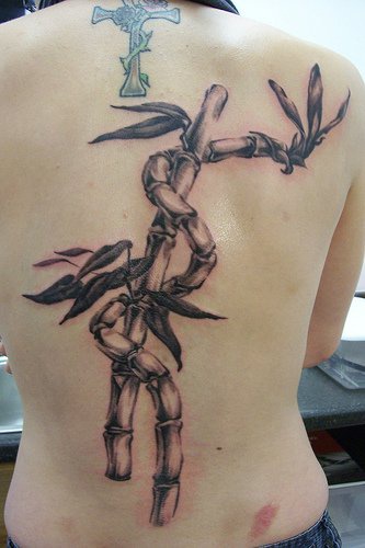 Tattoo mit Pflanze um Kreuz am oberen Rücken