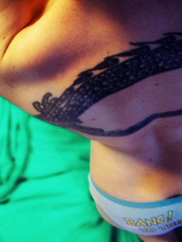 Schwarzes Tattoo mit geflochtenem Band am oberen Rücken