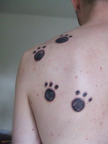 Schwarze Spuren eines Tieres am oberen Rücken Tattoo
