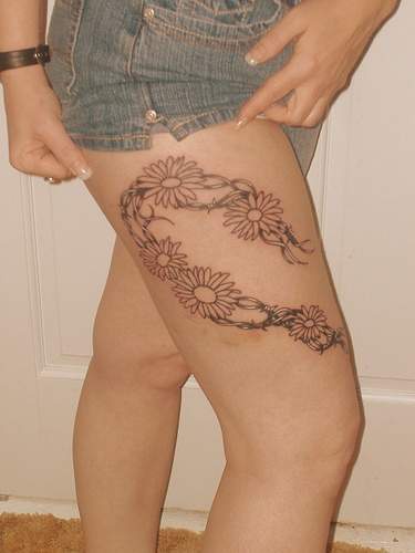 Blumen mit Stacheldraht Tattoo am Schenkel