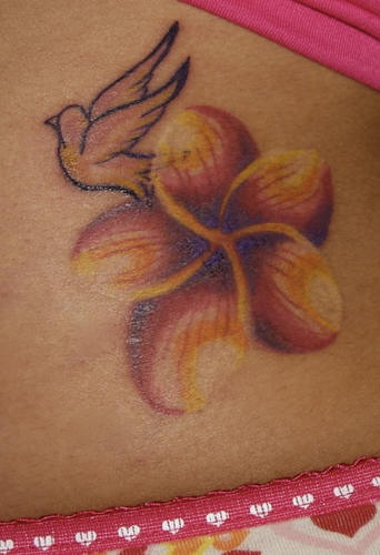 Lower back tattoo, white little bird and orange flower